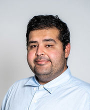 headshot of Dr. Waleed Jami with short wavy dark brown hair, mustache and goatee and wearing a light blue button down shirt
