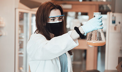 Ashlyn Grace Kelly holds a beaker while working in a lab.