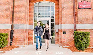 Caitlin and Joe hold hands while walking in front of Woodward Hall.