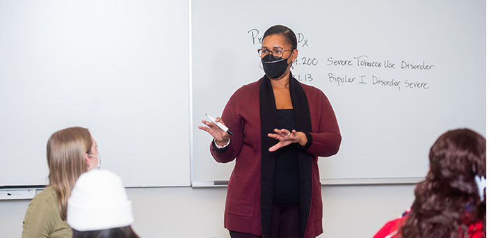 Professor Wendy Champagnie Williams teaches in front of a white board with 2 diagnoses written on it as students look on